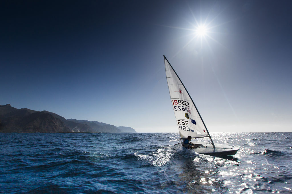 Persona navegando en velero bajo el sol cerca de la costa de Tenerife.