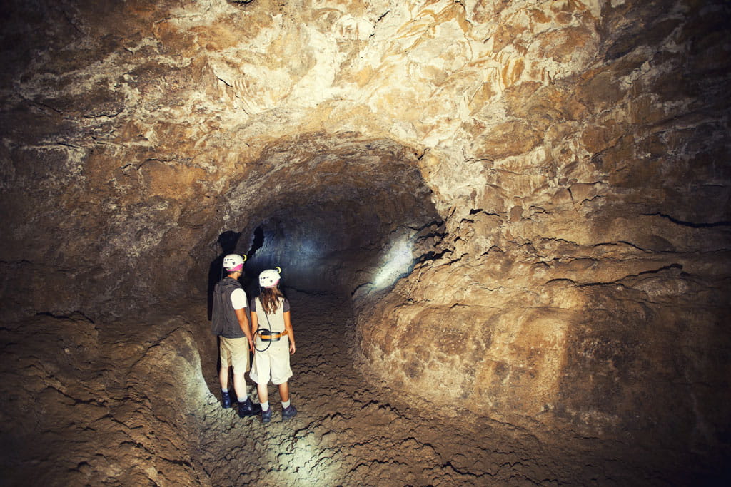 Exploradores con cascos caminan por un túnel en Cueva del Viento, Tenerife.