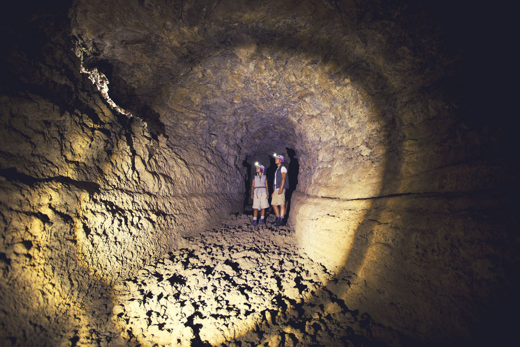 Exploradores con linternas en un túnel volcánico en Tenerife.