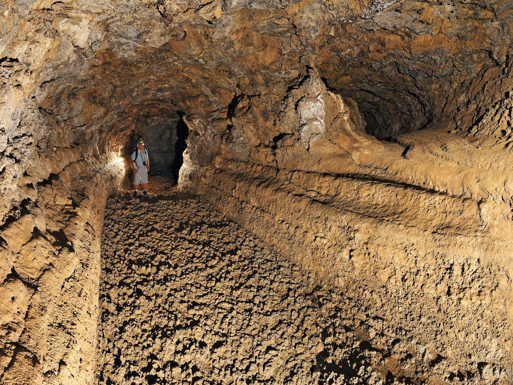 Persona explorando cueva volcánica en Tenerife.