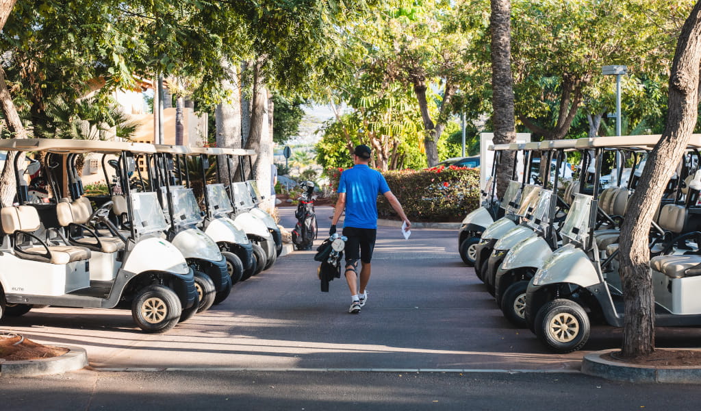 Hombre camina entre carritos de golf estacionados en Tenerife.