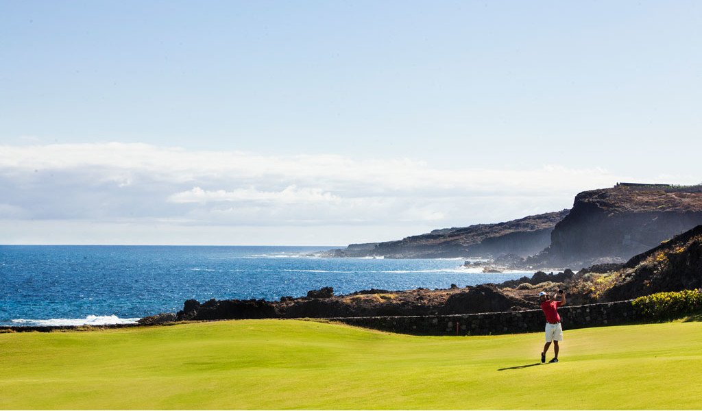 Persona jugando al golf cerca de la costa en Tenerife con el mar al fondo.