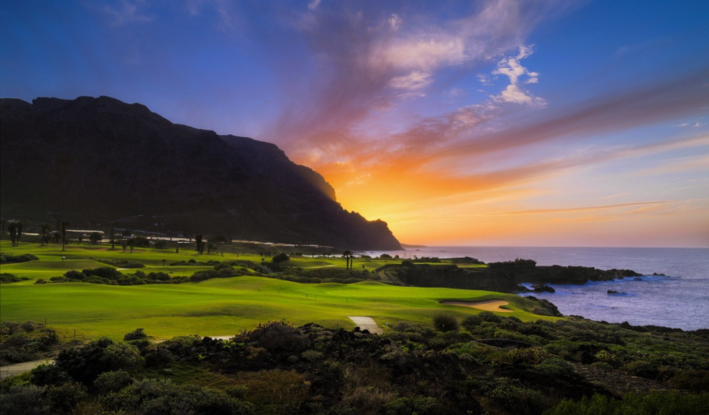 Atardecer sobre campo de golf en Tenerife junto al mar.