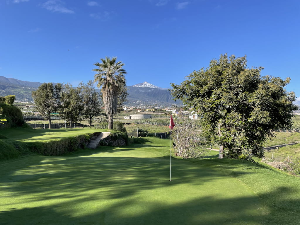 Campo de golf en Tenerife con el Teide al fondo y cielo despejado.