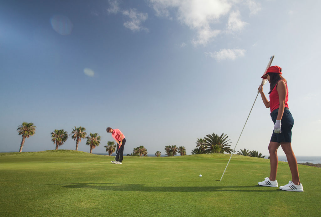 Jugadores de golf en el campo rodeado de palmeras en Tenerife.