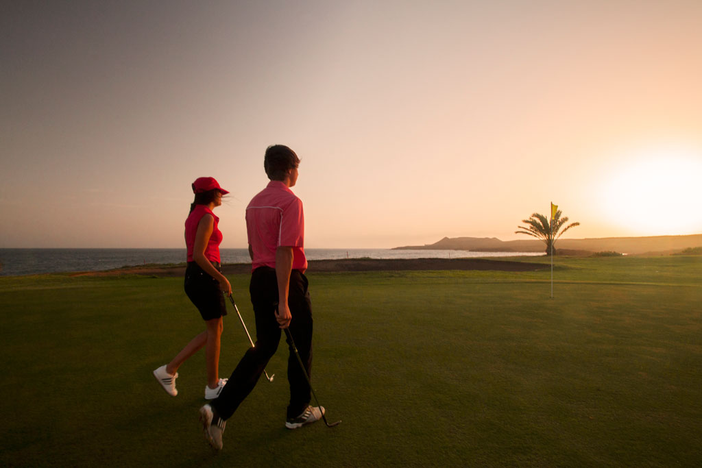 Personas jugando al golf al atardecer en la costa de Tenerife.