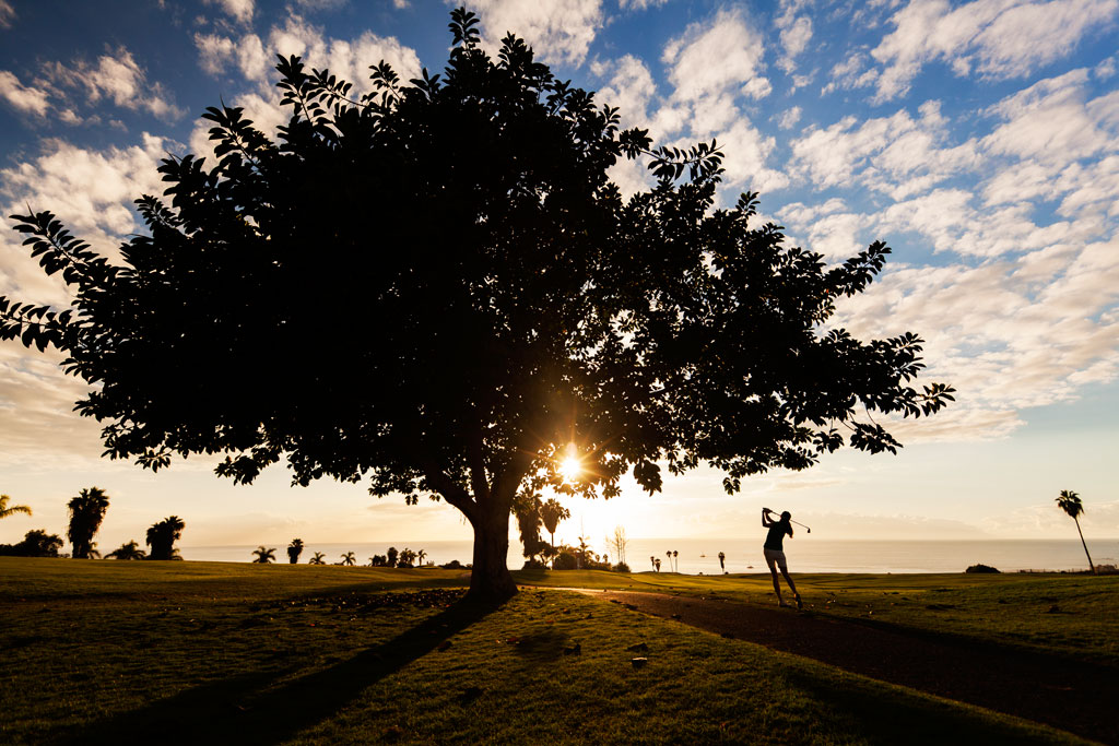 Persona jugando golf al atardecer en un campo de Tenerife.