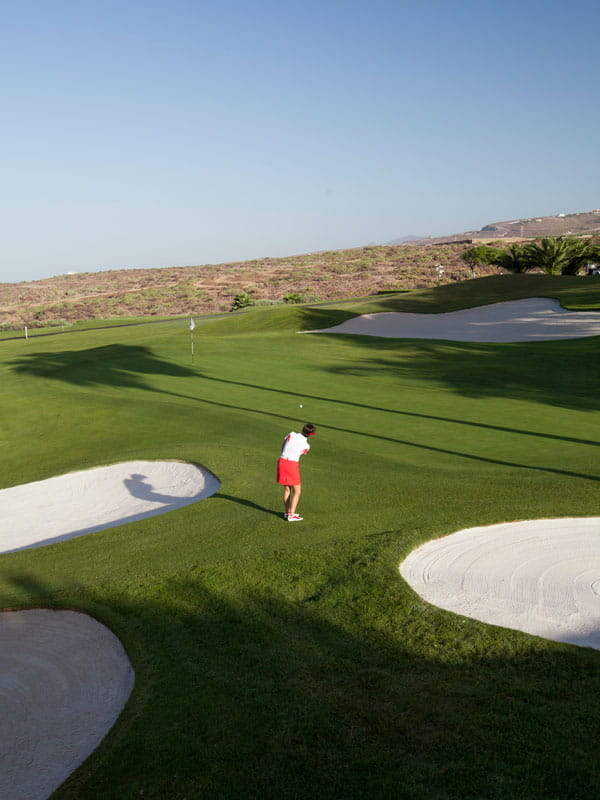 Jugador de golf en el campo de Abama en Tenerife, cerca del hoyo y un búnker.