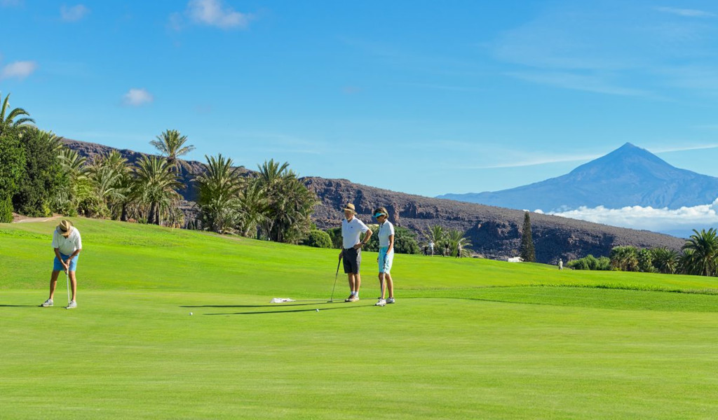 Jugadores de golf en un campo en Tenerife con el Teide al fondo.