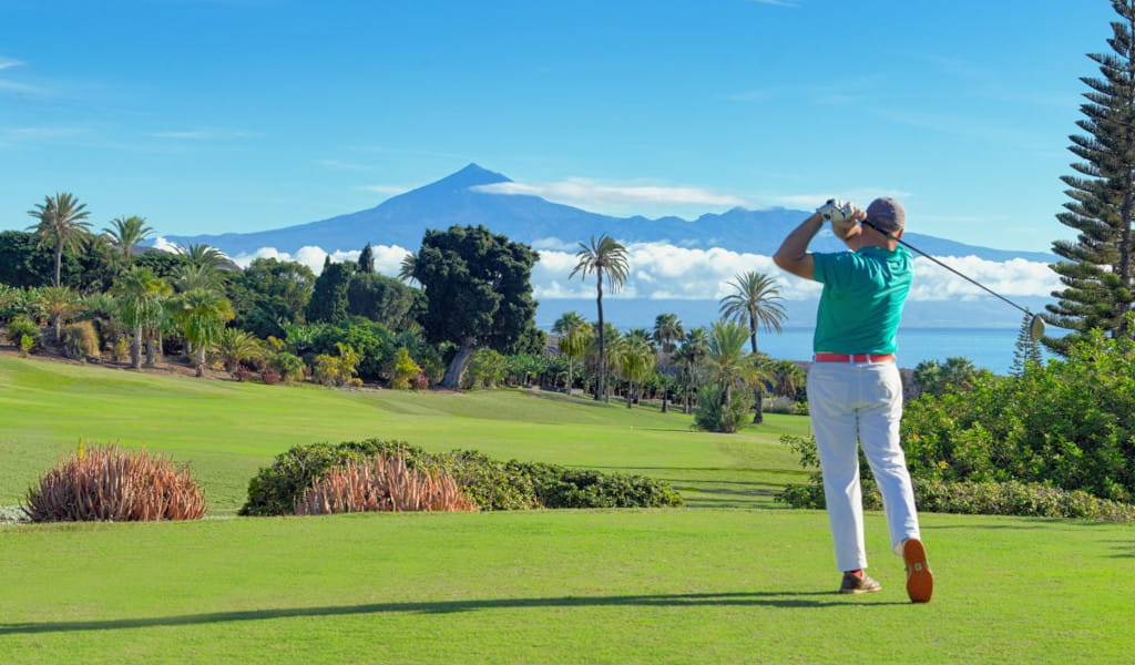 Golfista en acción con el monte Teide al fondo en Tenerife.