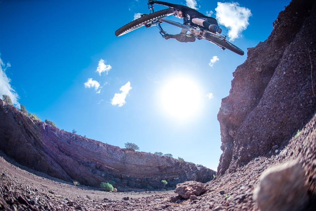 Ciclista en salto extremo en un cañón de Tenerife bajo cielo despejado.