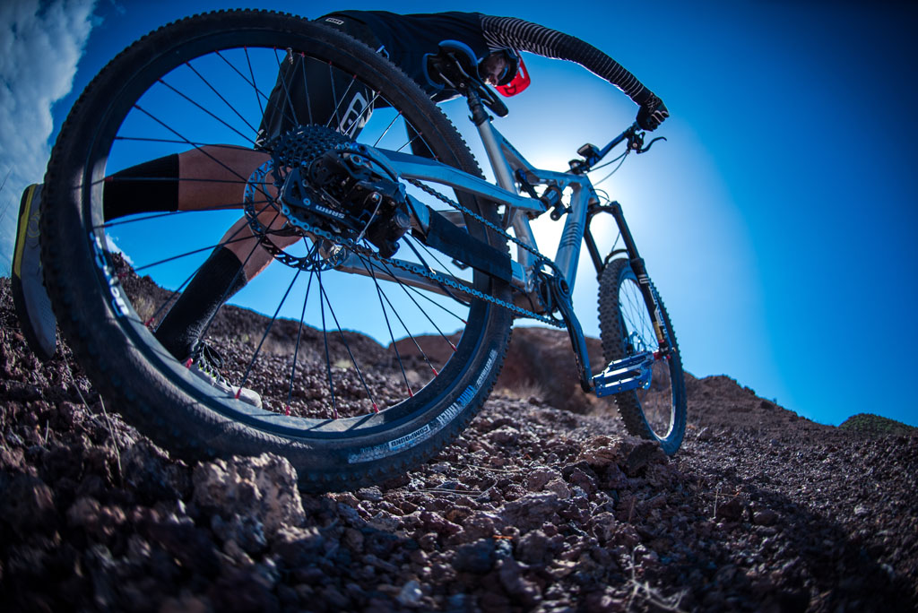 Ciclista en bicicleta de montaña sobre terreno rocoso en Tenerife bajo cielo azul.
