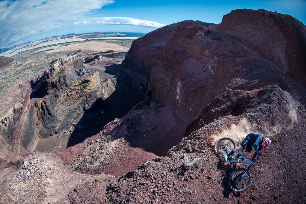 Ciclista descendiendo una ladera en una cantera en Tenerife, con vistas al mar.