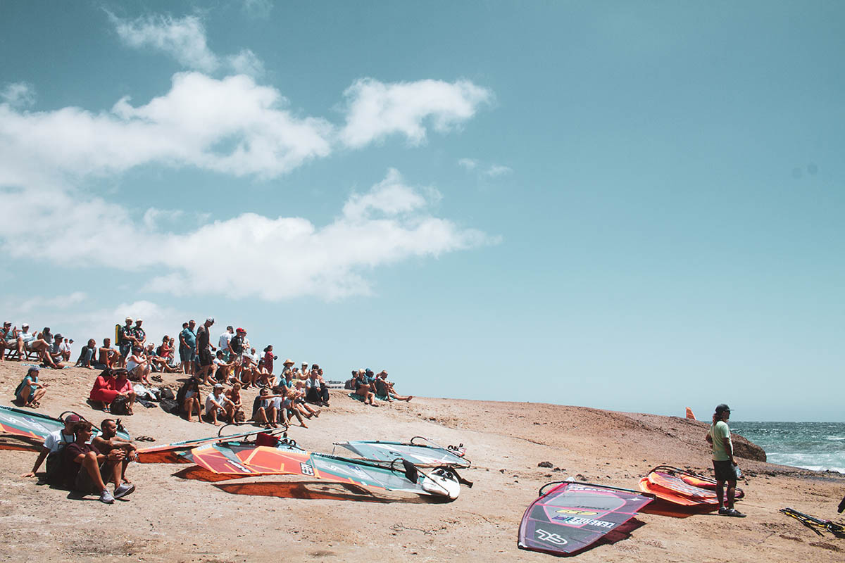 Personas reunidas en la playa con tablas de windsurf en El Médano, Tenerife.