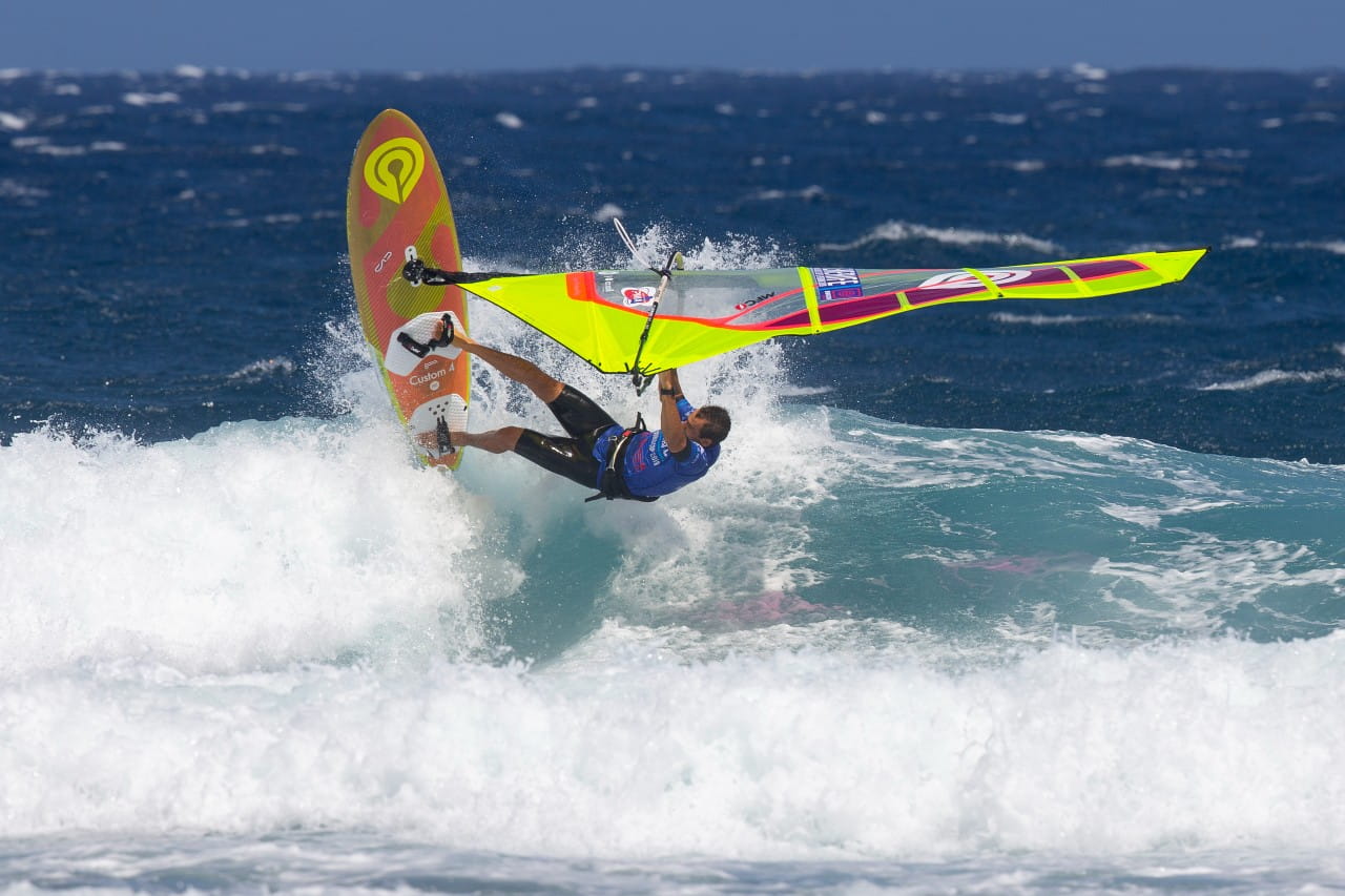 Persona practicando windsurf en El Médano, Tenerife sobre una ola.