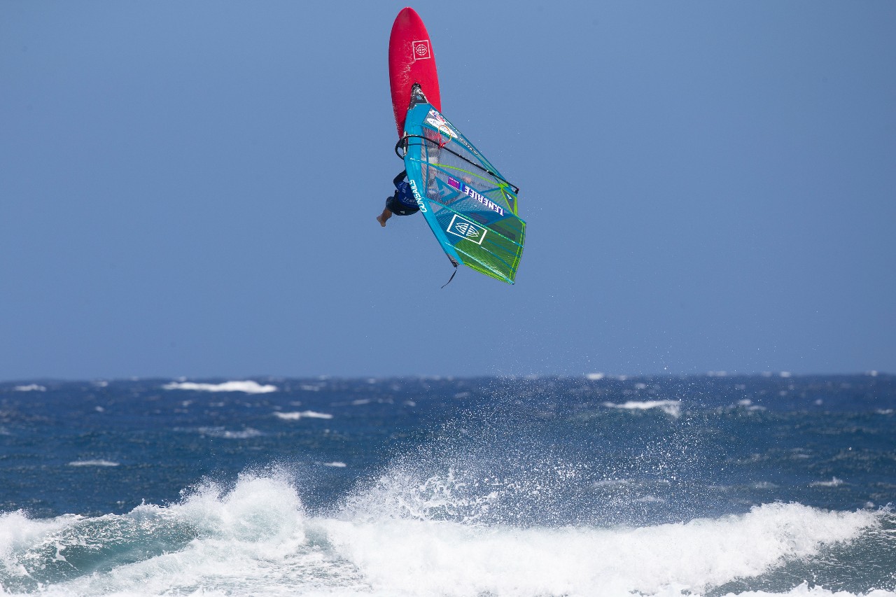 Persona practicando windsurf en el Médano, Tenerife, realizando un salto sobre el mar.