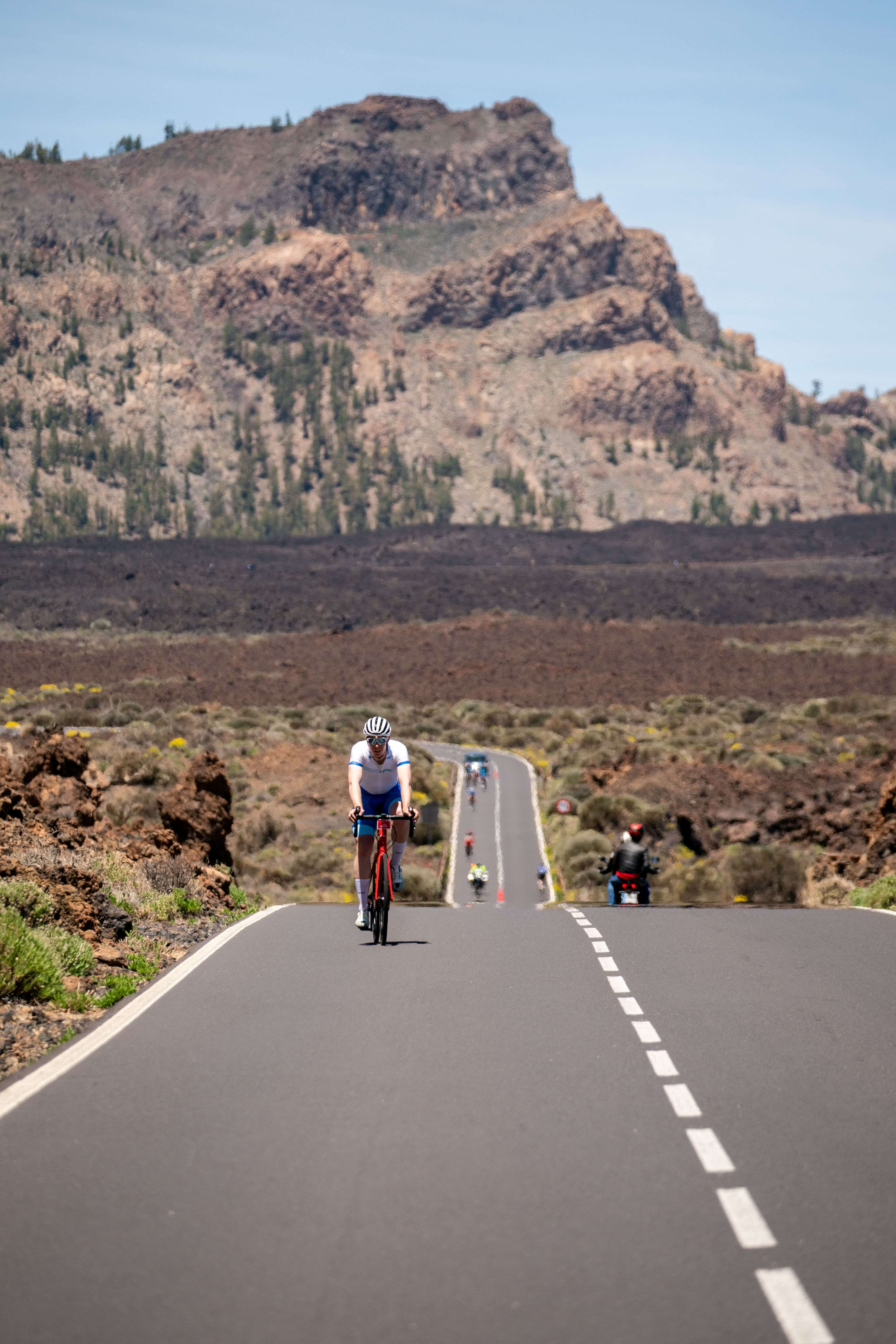 Ciclista en carretera hacia el Teide en Tenerife, rodeado de paisaje volcánico.