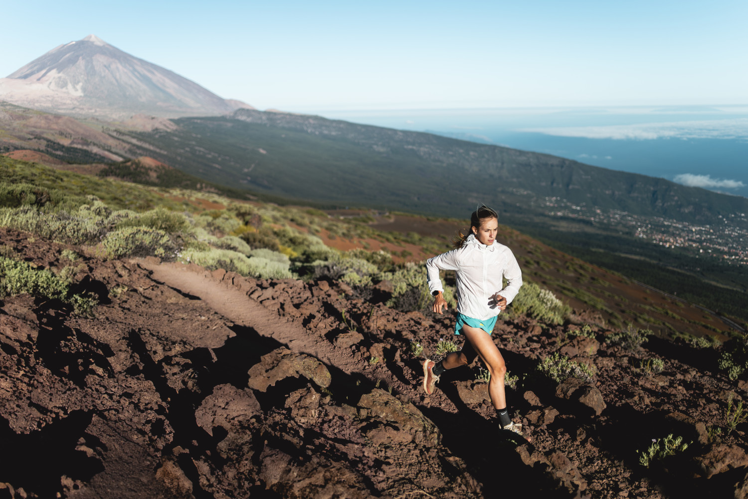 Persona corriendo en sendero cerca del Teide, Tenerife, con vistas al paisaje.