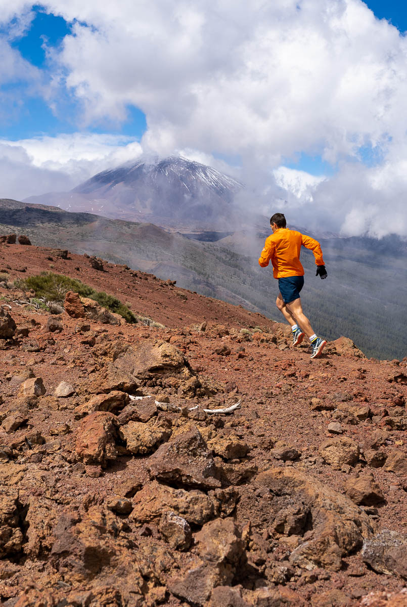 Corredor en el sendero del Teide, Tenerife, con cielo nublado y montaña al fondo.