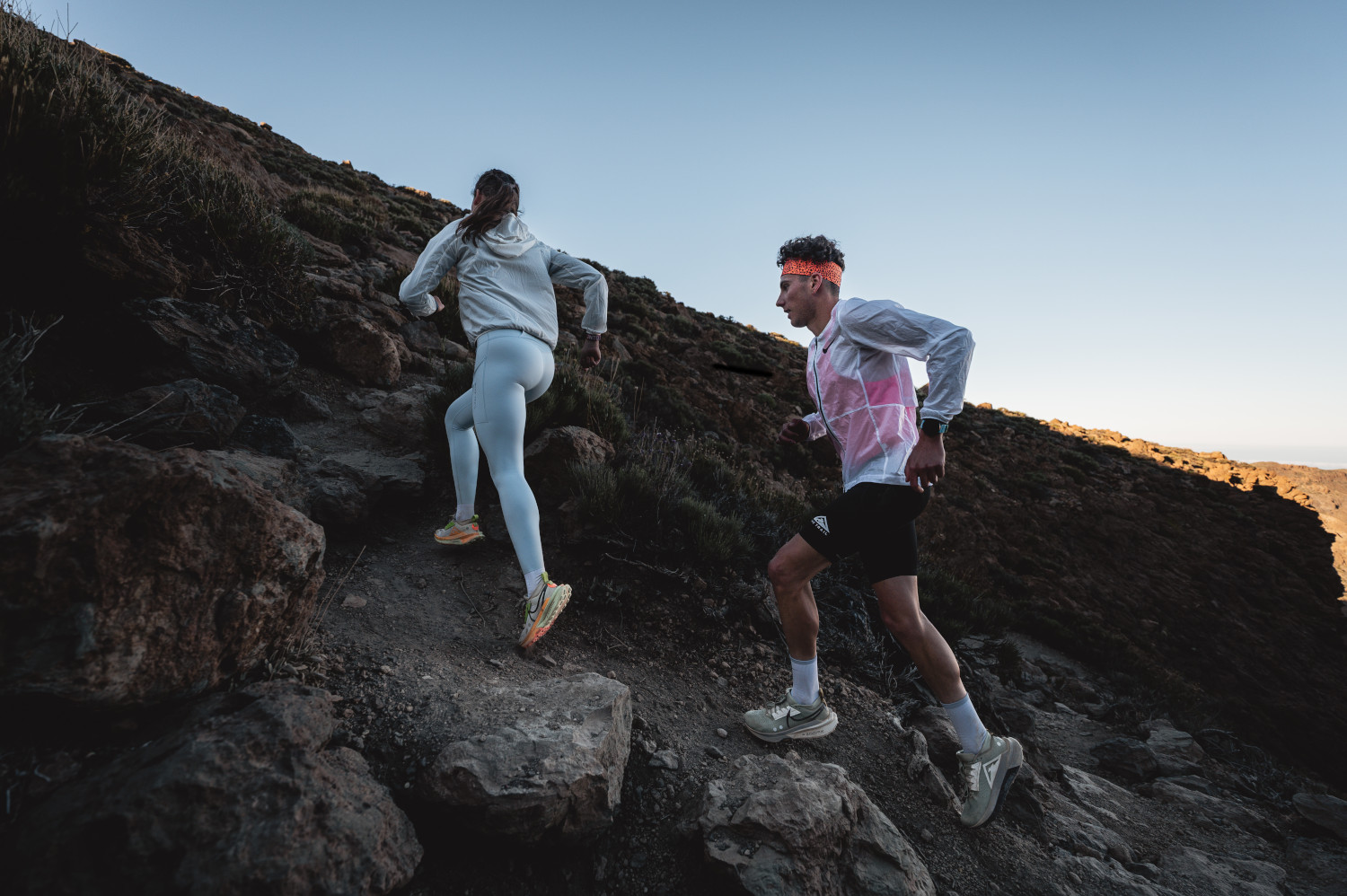 Personas corriendo por un sendero rocoso en Tenerife al amanecer.