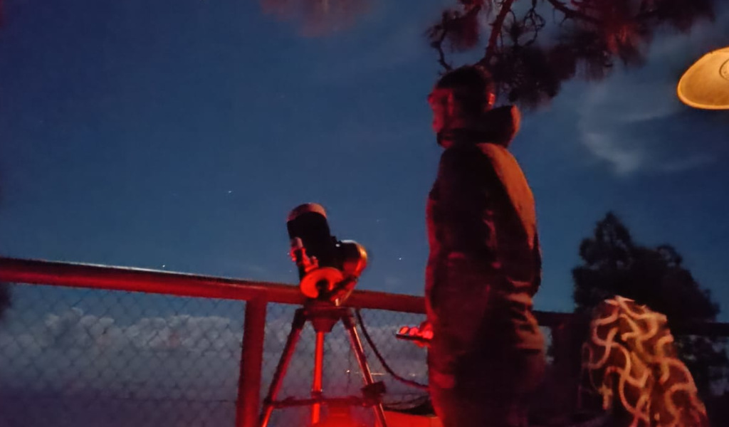 Persona observando el cielo nocturno con telescopio, posiblemente en Tenerife.
