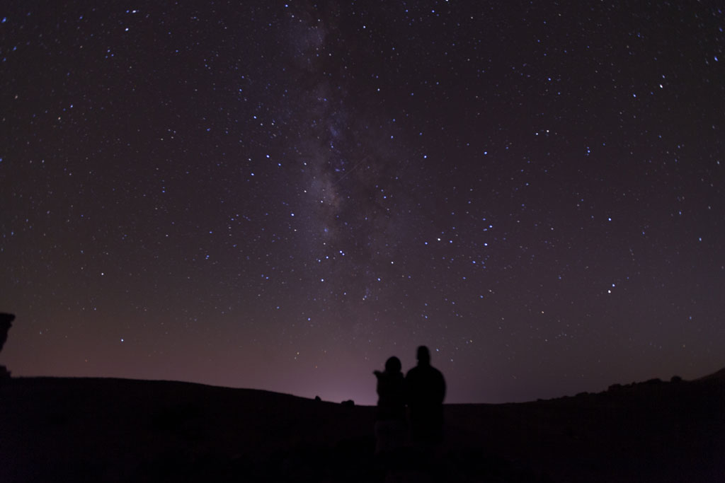 Cielo estrellado sobre el Teide en Tenerife con dos siluetas observando.