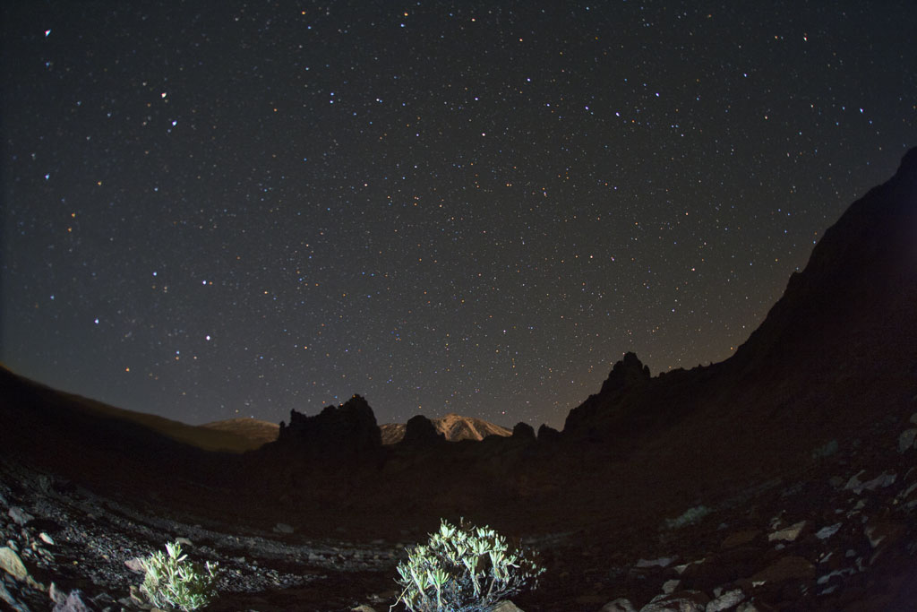Cielo estrellado sobre el Teide en Tenerife con montañas en la oscuridad.