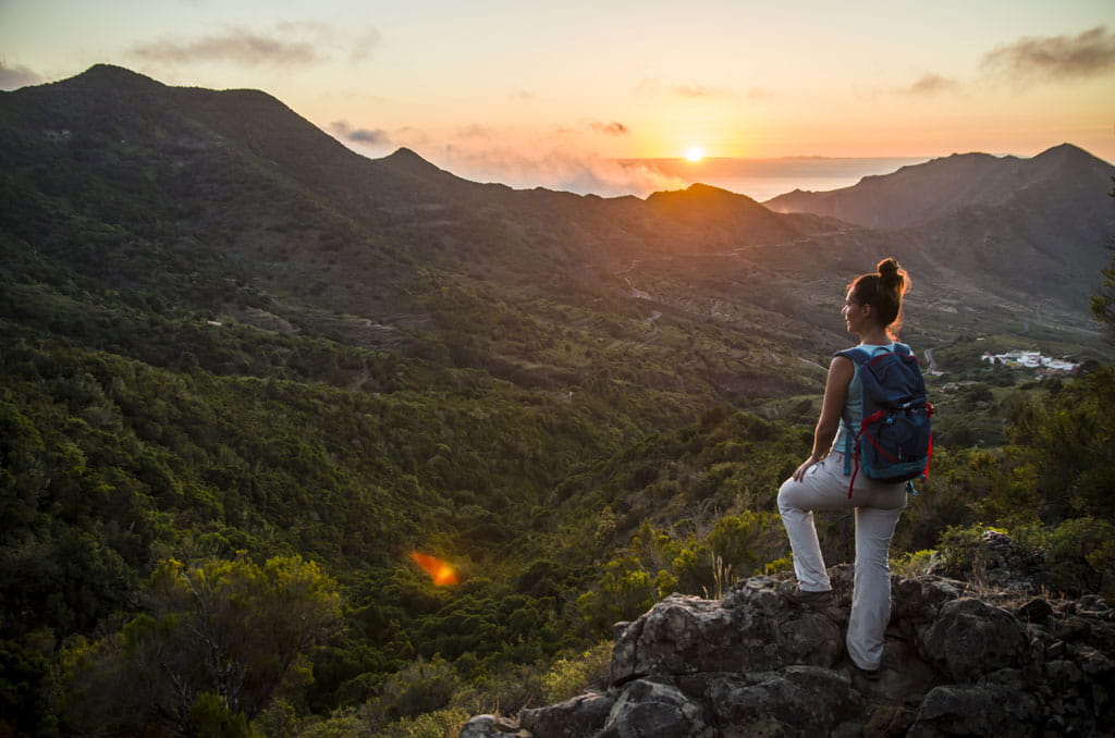 Persona con mochila observa el atardecer desde un mirador en las montañas de Tenerife.