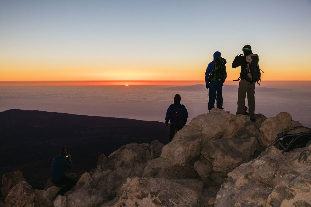 Montañistas observando el amanecer desde la cumbre del Teide en Tenerife.