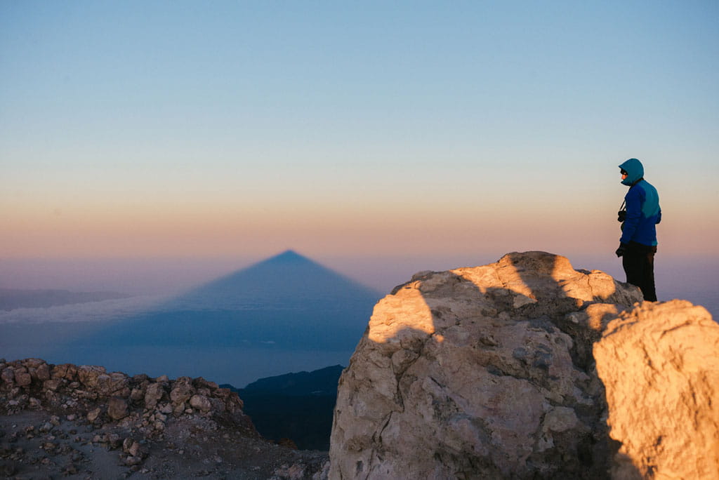 Persona observando sombra del Pico del Teide al amanecer en Tenerife.