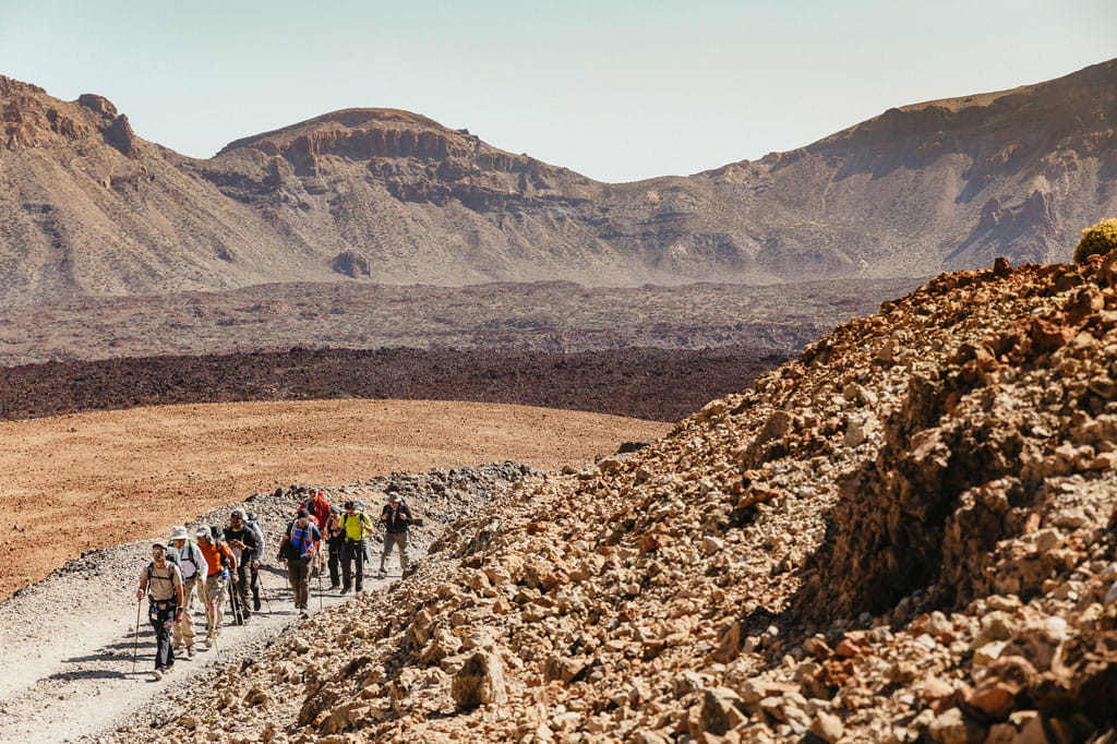 Grupo de senderistas en un camino rocoso en el Parque Nacional del Teide, Tenerife.