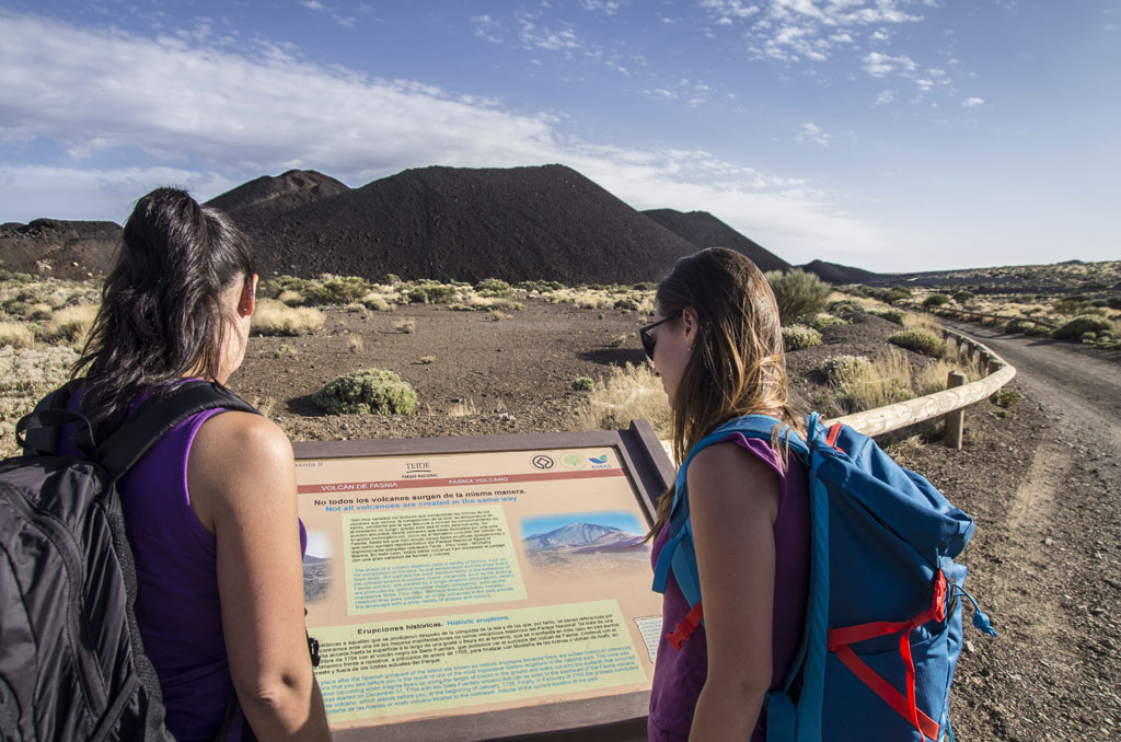 Dos personas leen un cartel informativo sobre el volcán Fasnia en el Parque Nacional del Teide.
