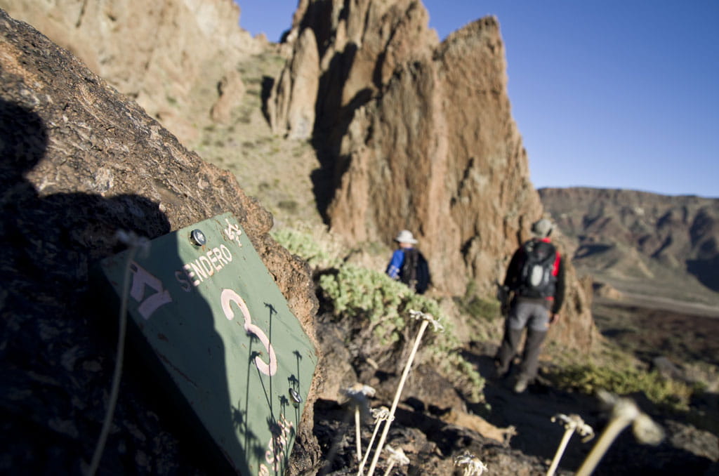 Sendero 3 en Tenerife con dos excursionistas caminando cerca de formaciones rocosas.