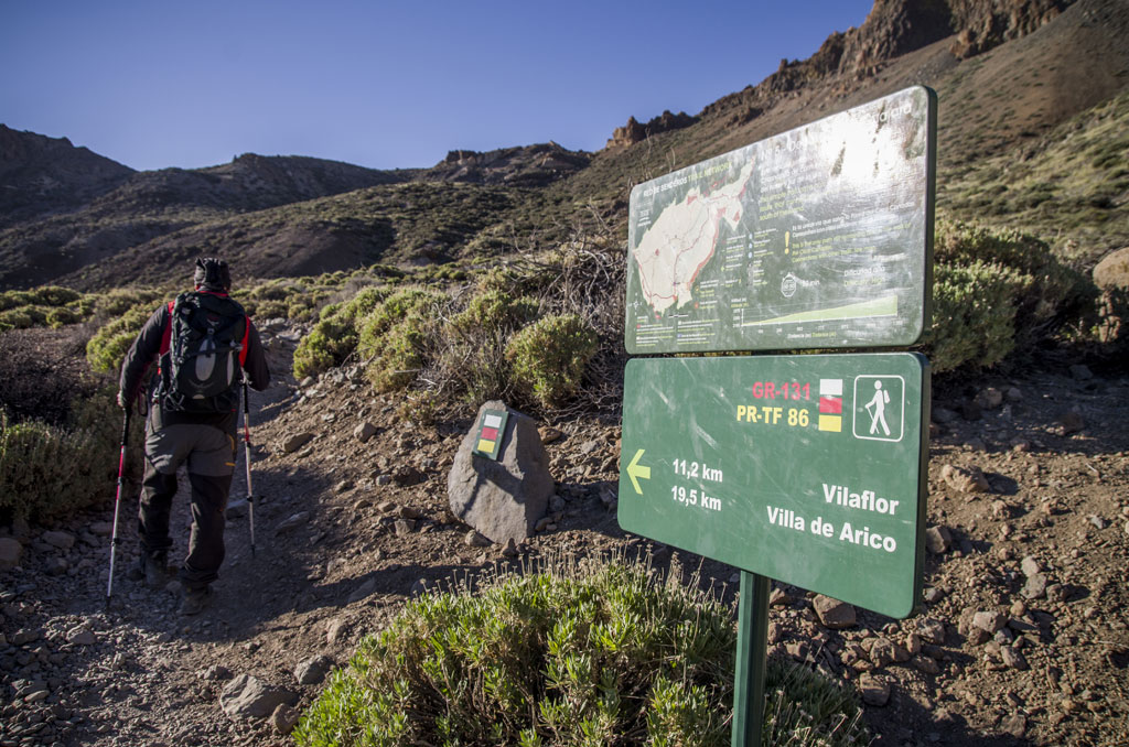 Senderista en camino hacia Vilaflor, Tenerife, junto a señal de rutas y distancias.