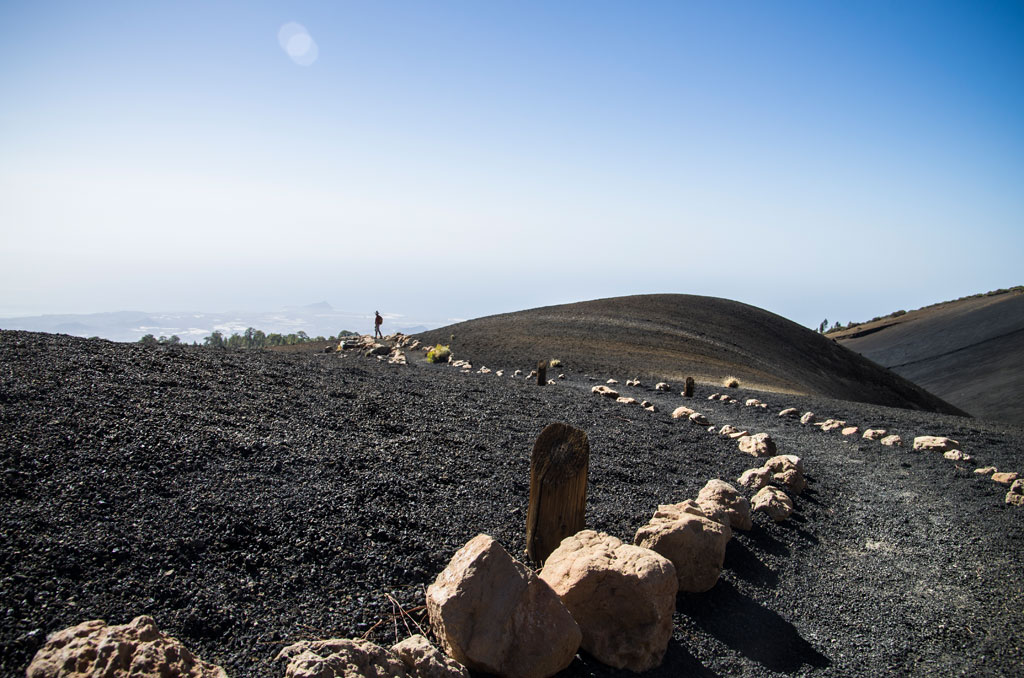 Sendero volcánico en Tenerife con un horizonte despejado y cielo azul.