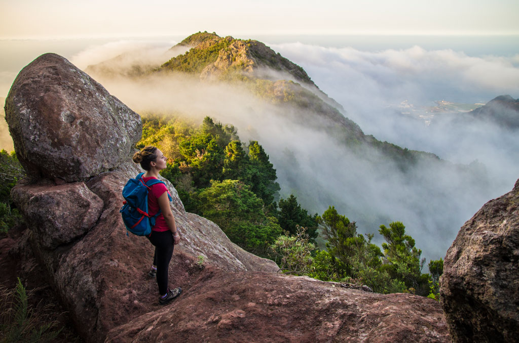 Persona con mochila observa montañas y nubes en Tenerife.