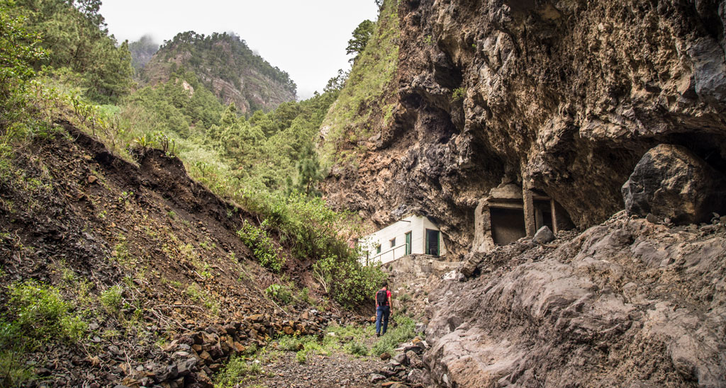Sendero rocoso con un excursionista cerca de una cueva en Anaga, Tenerife.