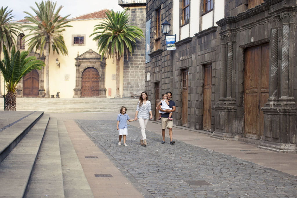 Familia caminando por calle con edificios históricos en La Laguna, Tenerife.