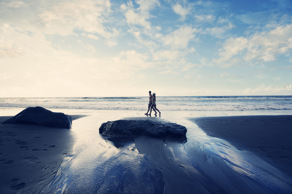 Personas caminando por la playa en Tenerife al atardecer.