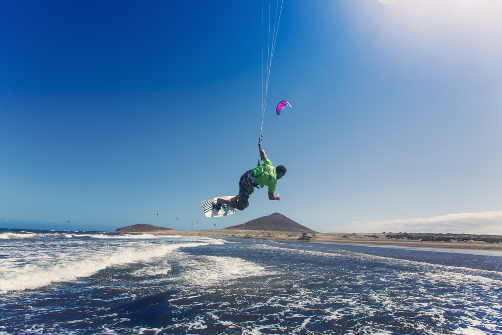 Persona practicando kitesurf en playa El Médano, Tenerife, con cielo despejado.