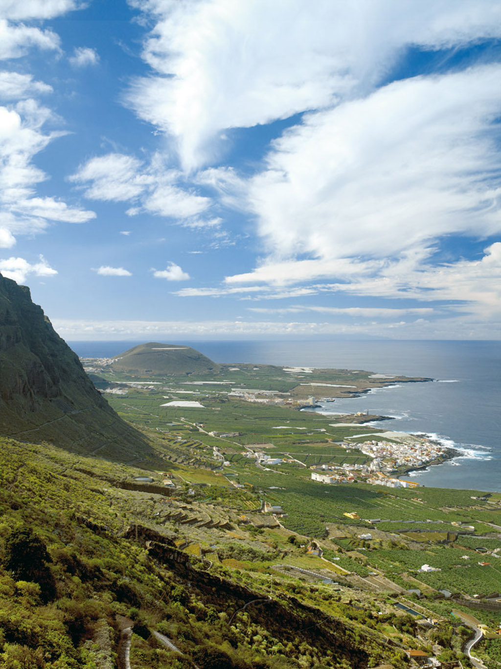 Vista panorámica de Garachico, Tenerife, con montañas y el océano Atlántico al fondo.