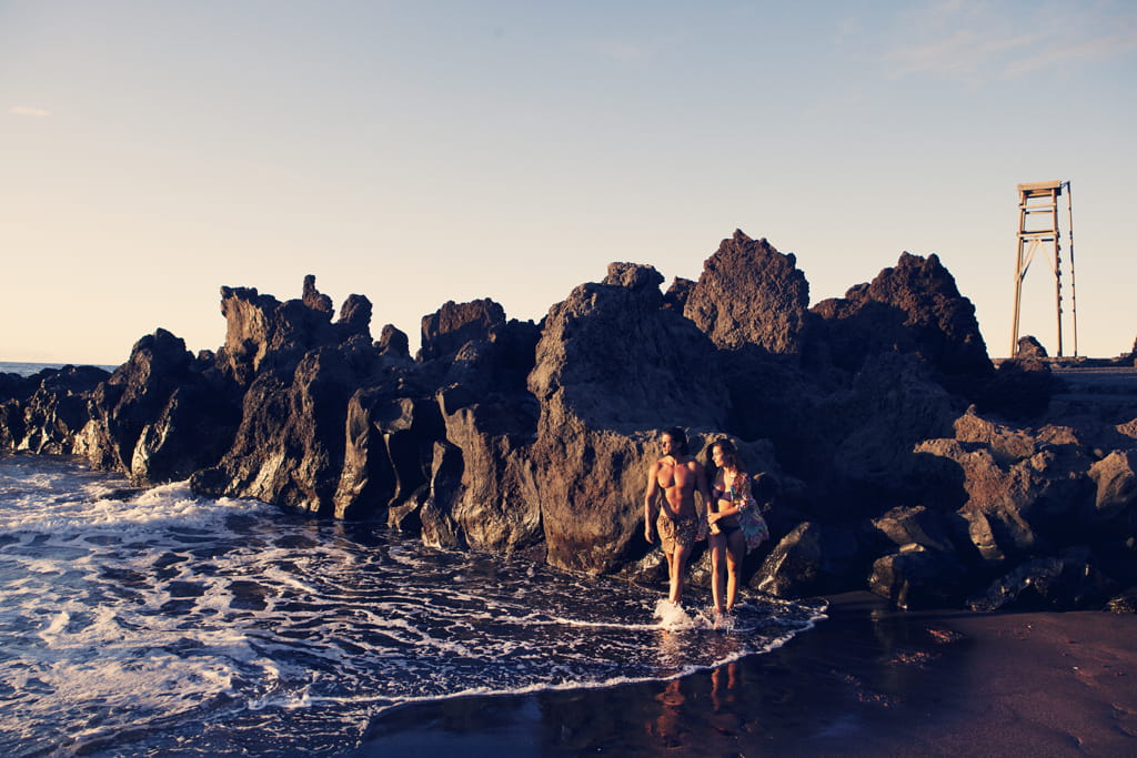 Personas caminando por la playa junto a rocas en Bajamar, Tenerife.