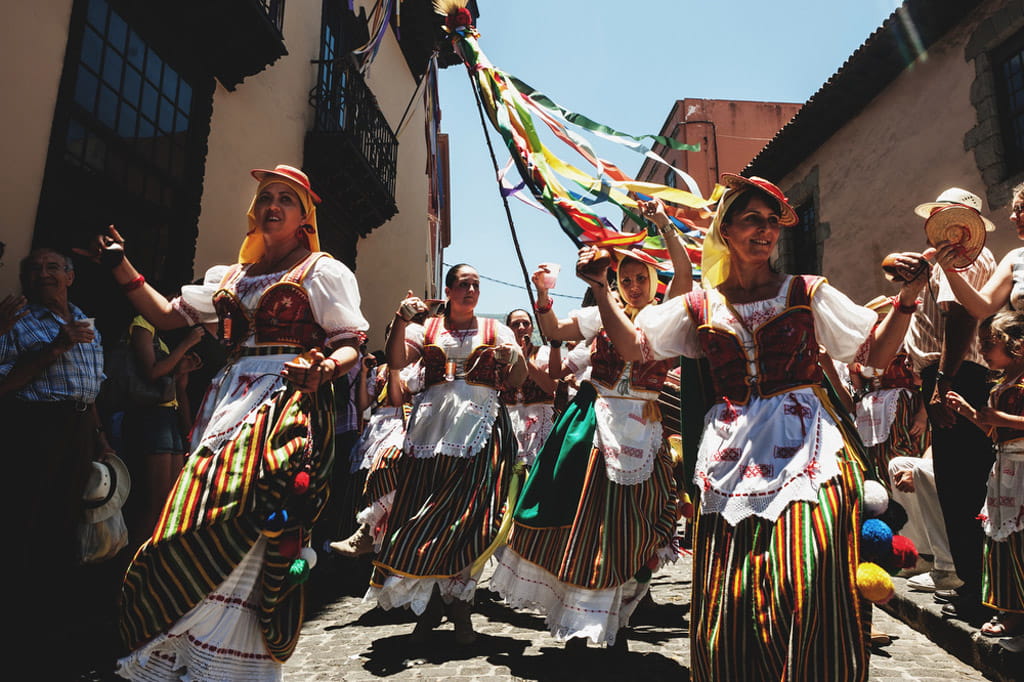 Personas en vestidos tradicionales bailan en una calle de Tenerife.