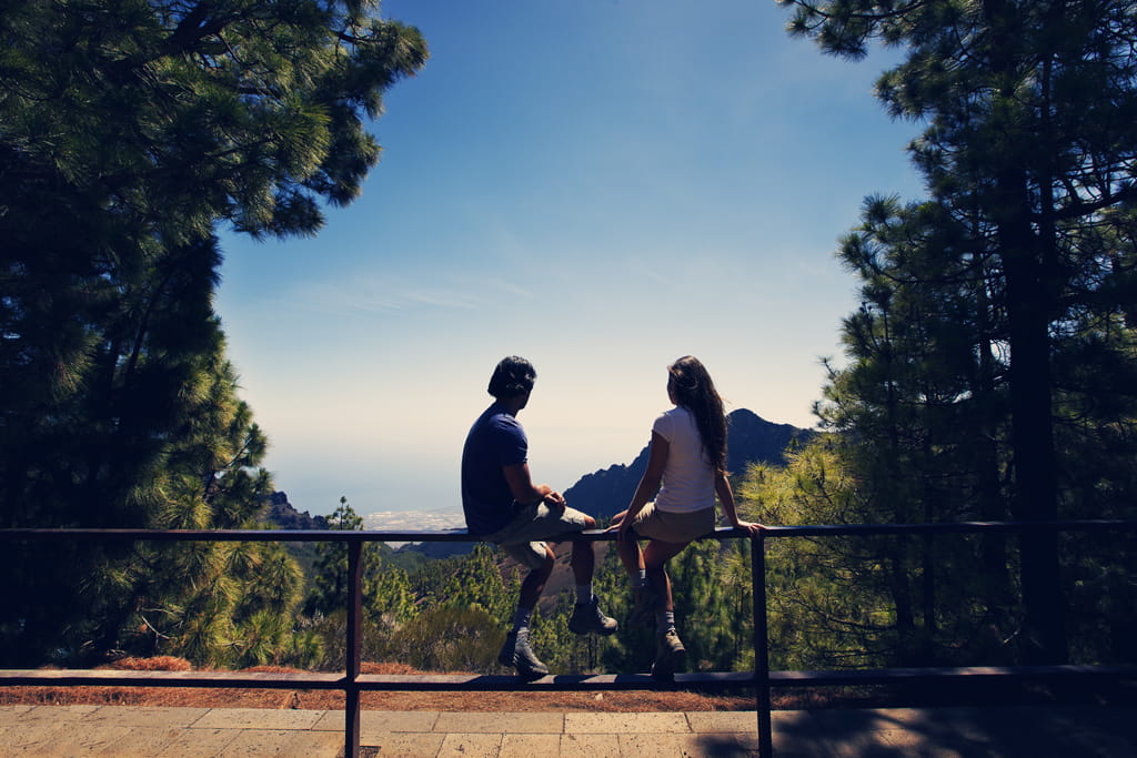 Dos personas sentadas en un mirador con vistas al mar en Tenerife.