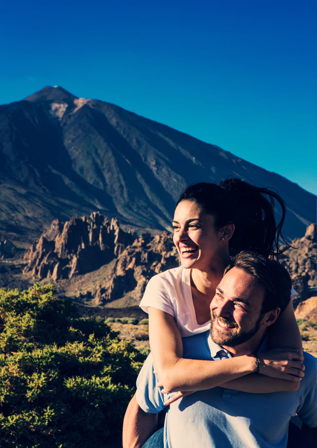 Pareja sonriendo con el Teide en Tenerife al fondo.