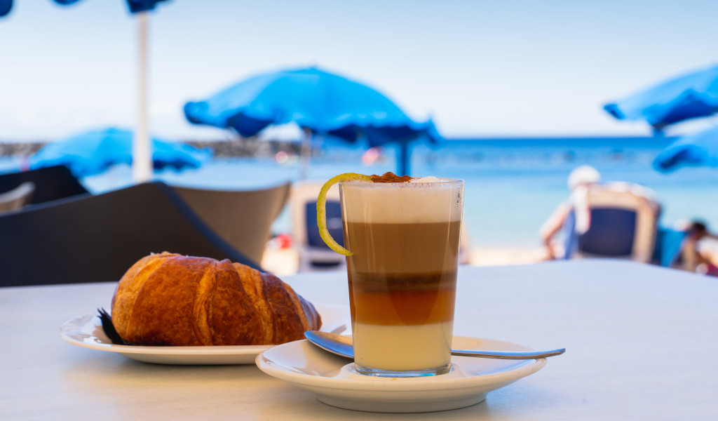 Café barraquito y croissant junto al mar en Tenerife.