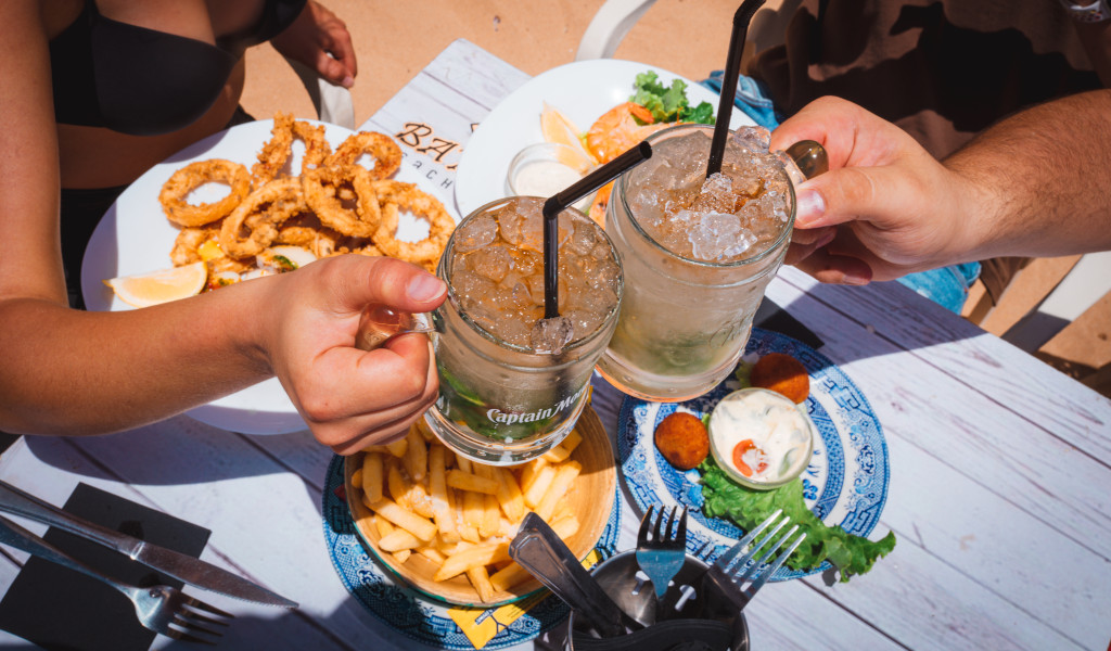Dos personas brindando sobre una mesa con calamares y patatas en Tenerife.