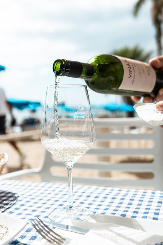 Vino blanco siendo servido en copa sobre mesa con mantel a cuadros en Tenerife.