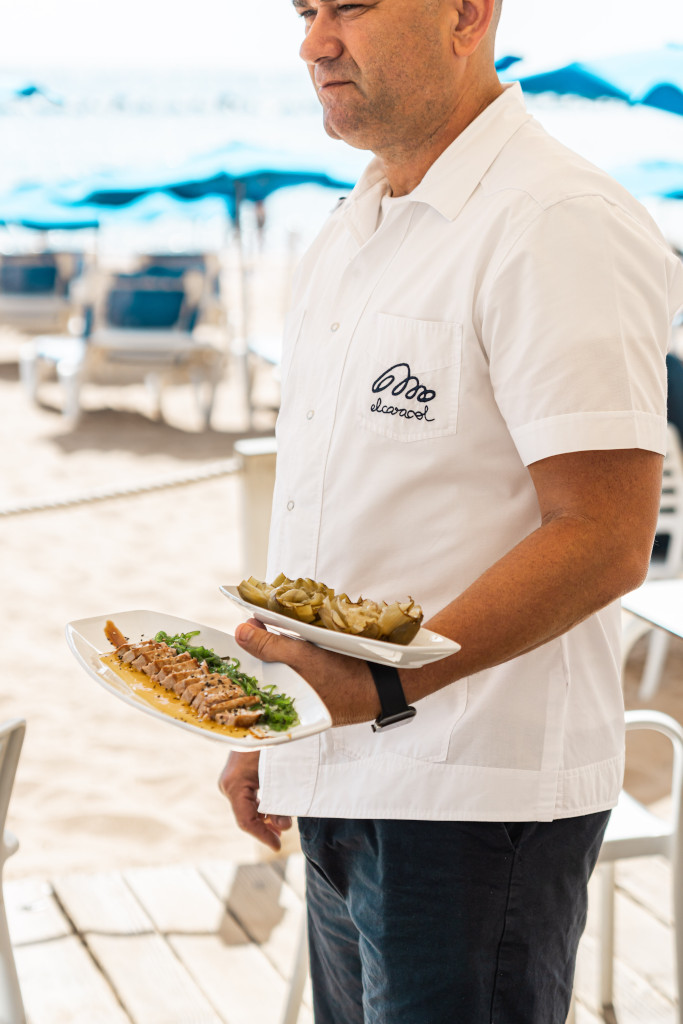 Persona sirviendo platos de comida en una playa de Tenerife.