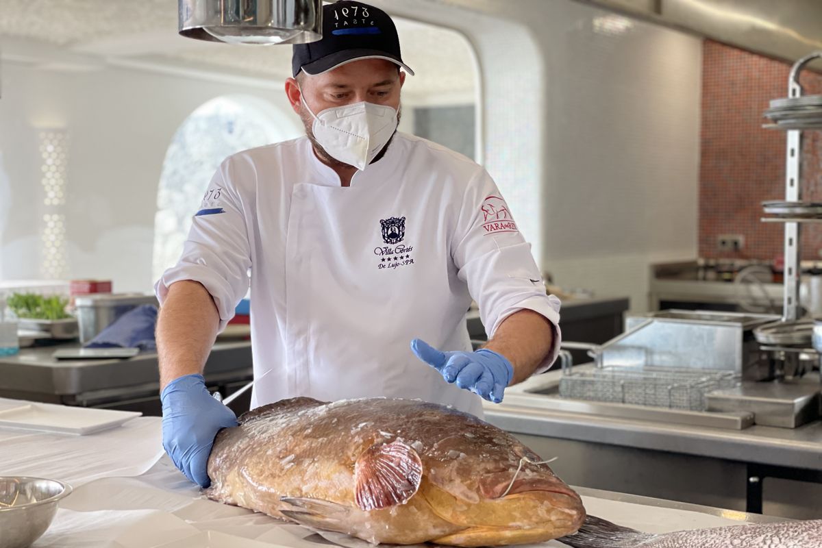 Chef en Tenerife preparando un pescado fresco en la cocina.